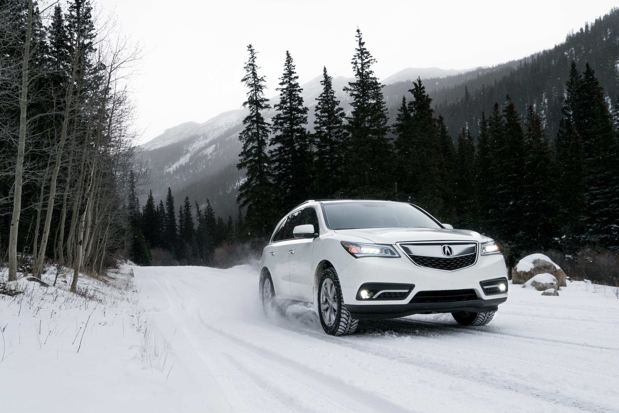 White Acura MDX drives up a snowy mountain road in Colorado