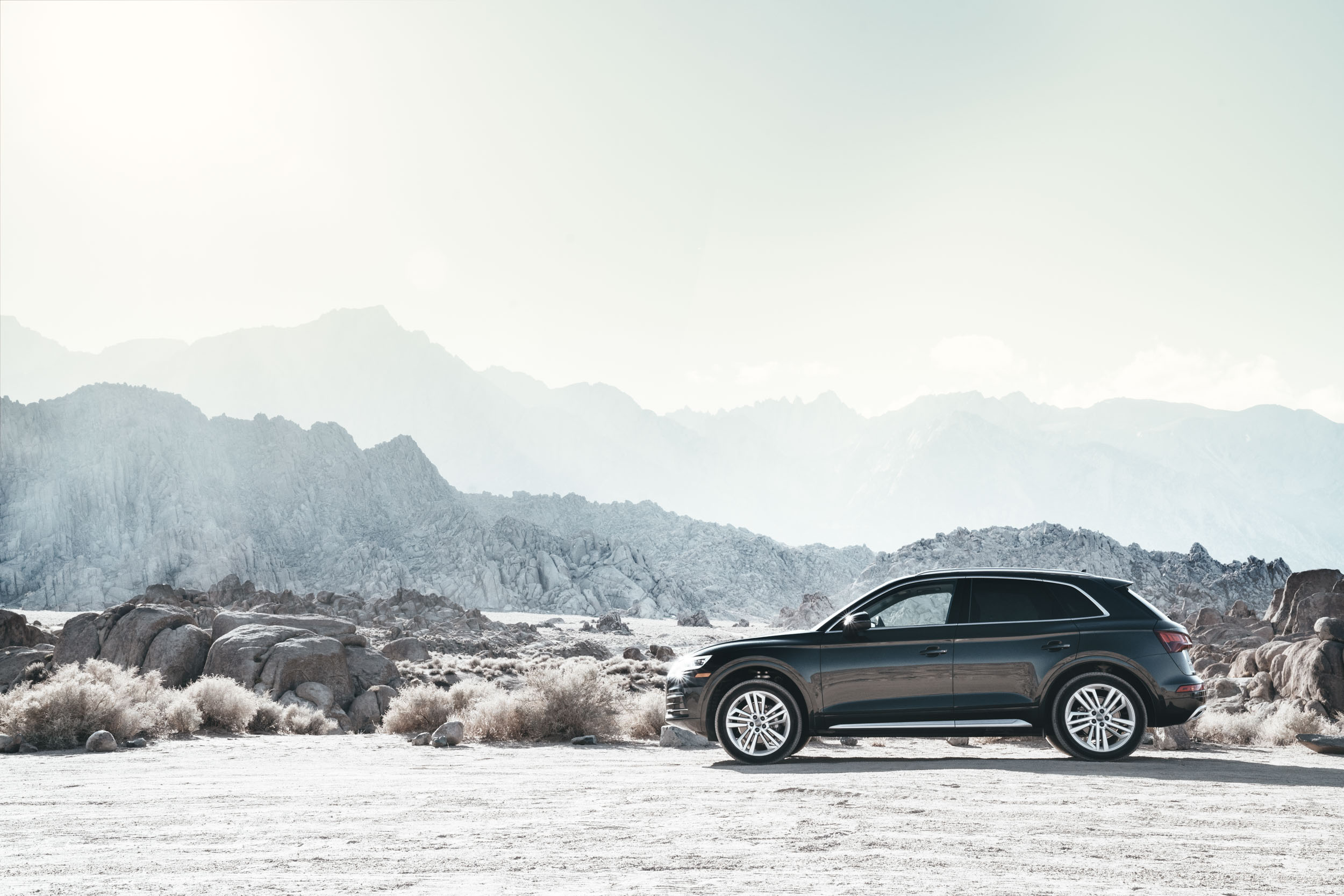 Black Audi Q5 sits in a bleak desert environment with mountains in background
