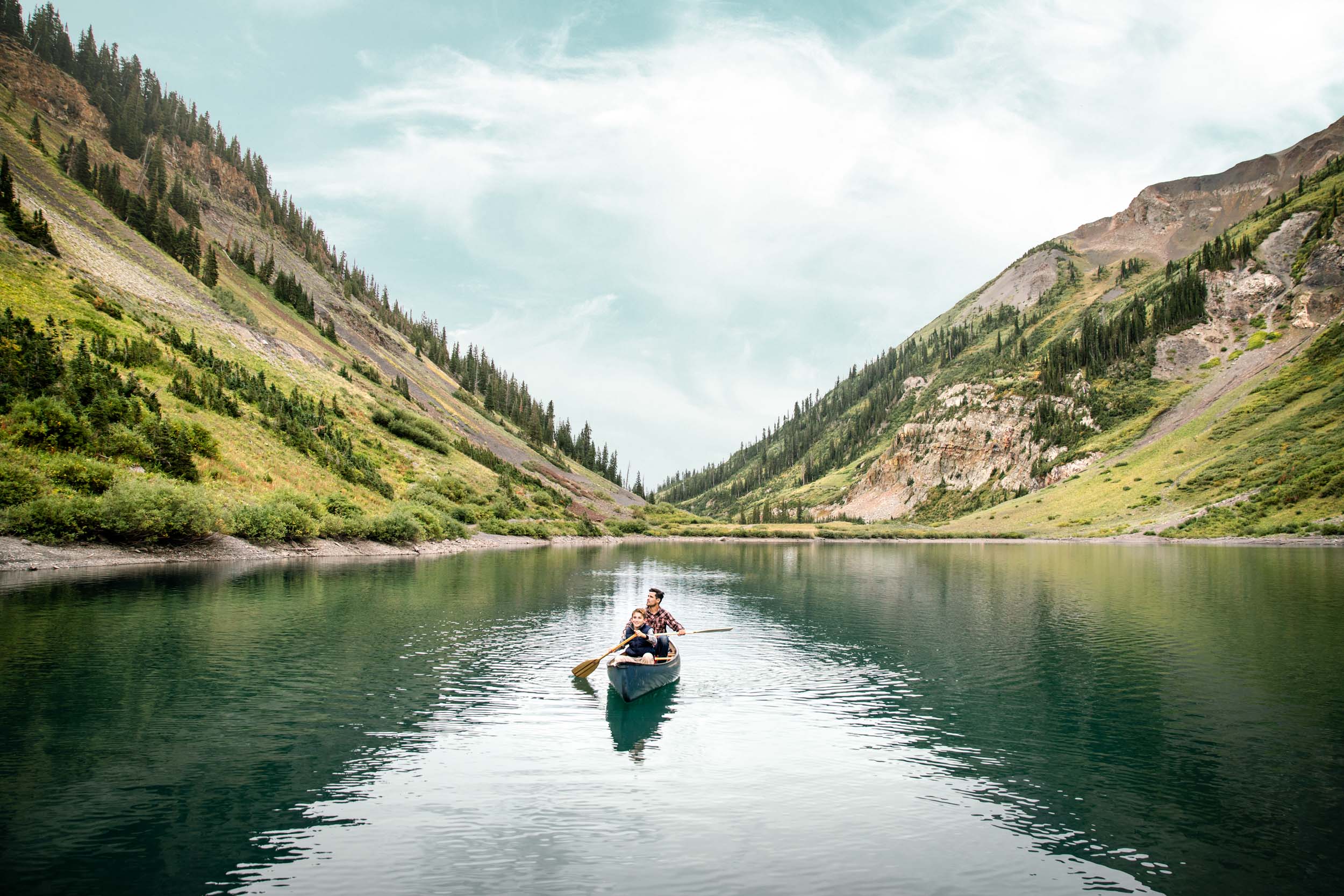 Father and son canoeing together in a mountain lake in the Colorado rockies.