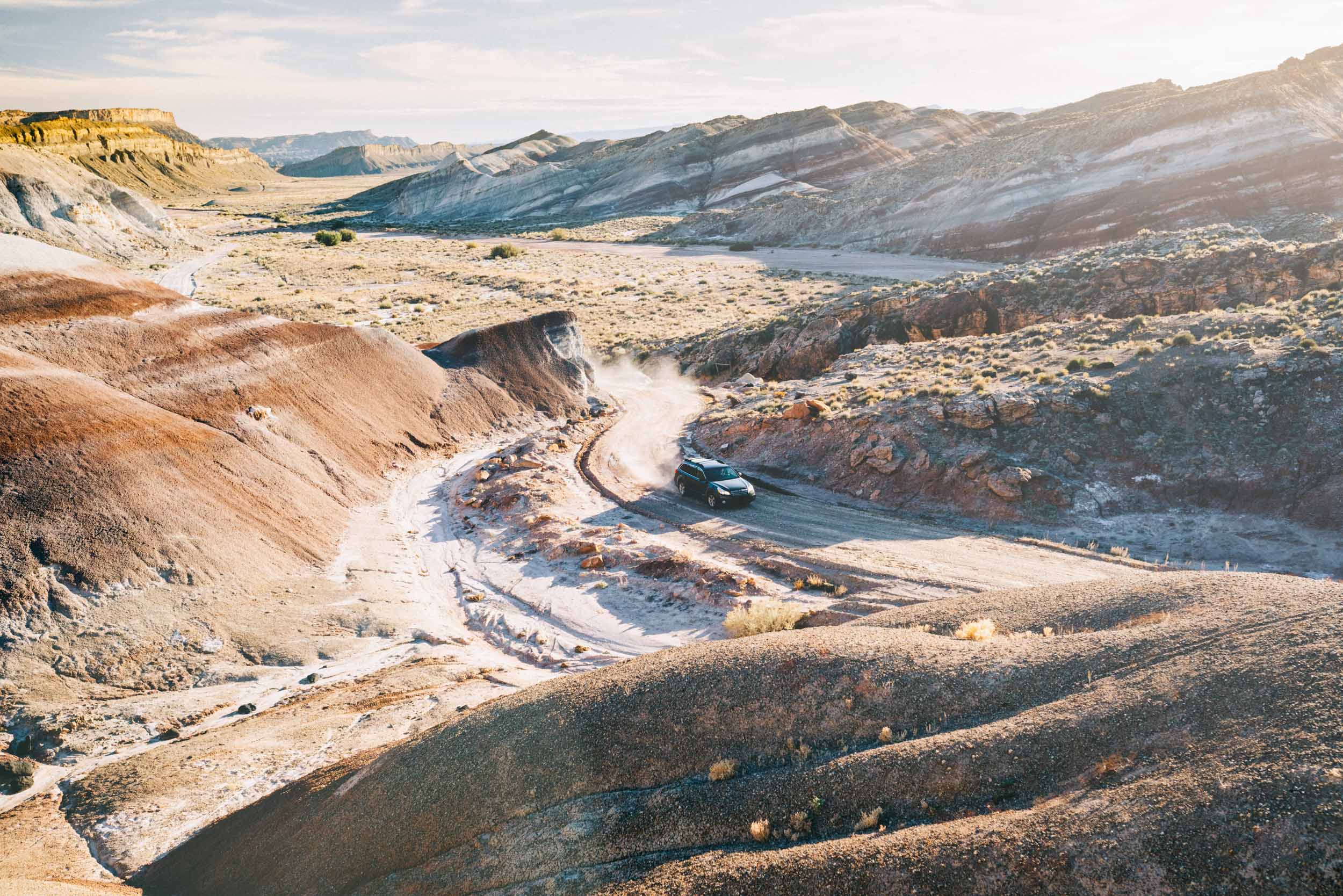 Grey Subaru Outback drives down a curvy desert road in Capitol Reef National Park Utah
