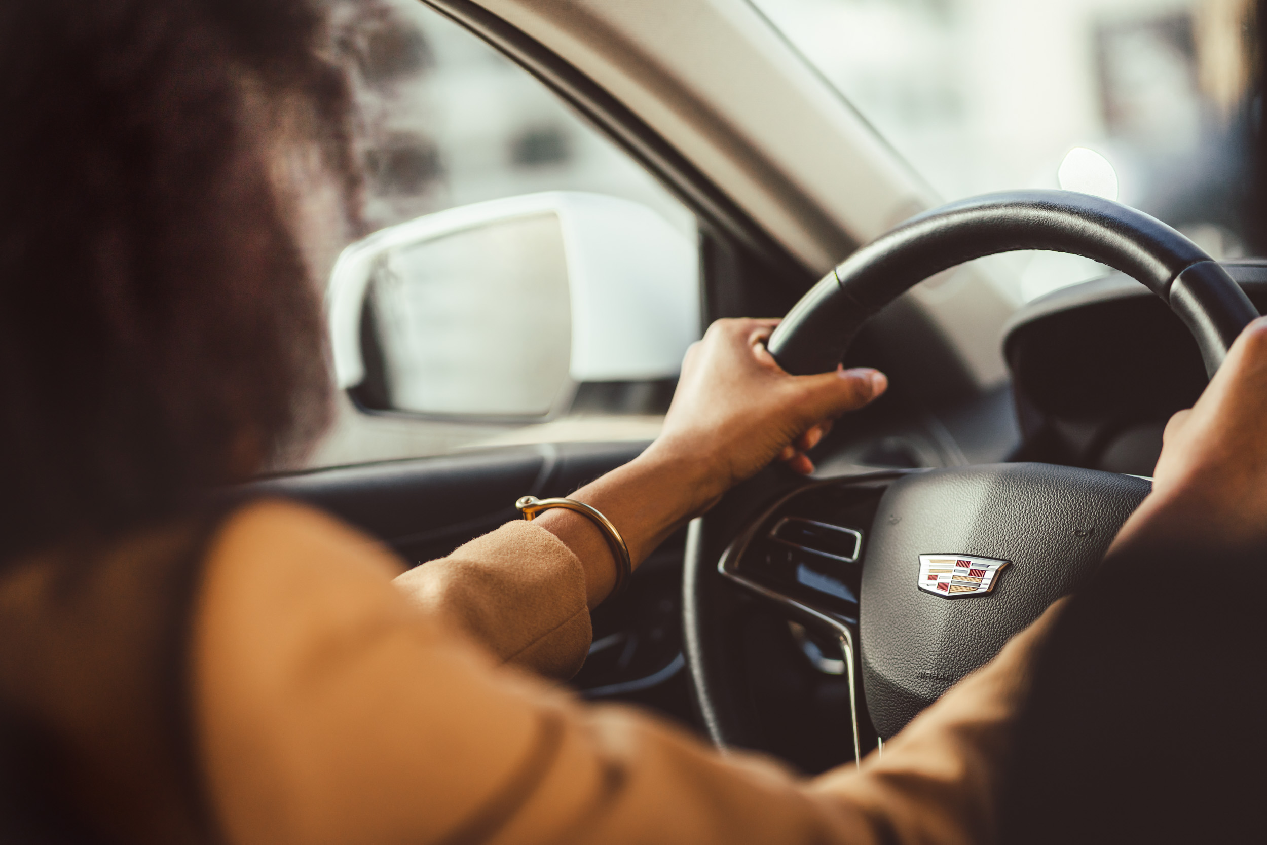 An interior shot of a female model driving her car with her hands on the steering wheel