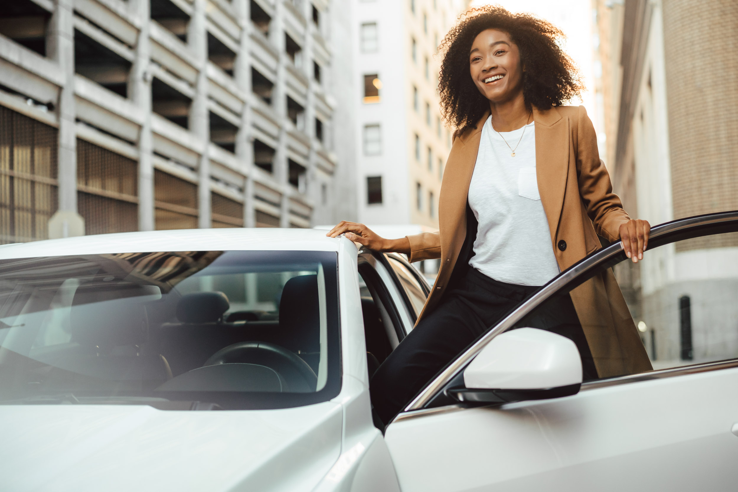 A female model exits the drivers side door of her white Cadillac ATS