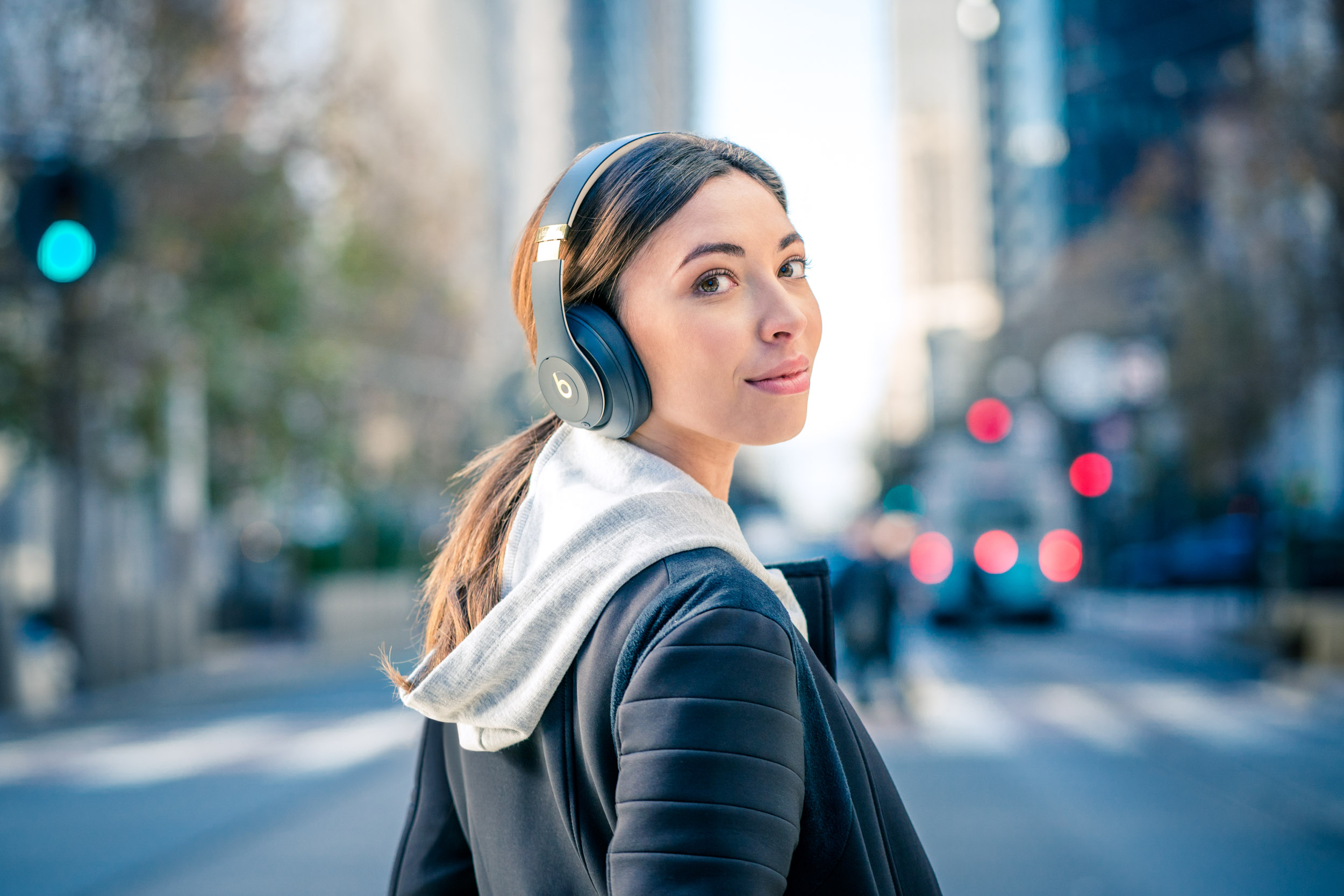 Female wearing Beats headphones looks over her shoulder while crossing street in San Francisco 