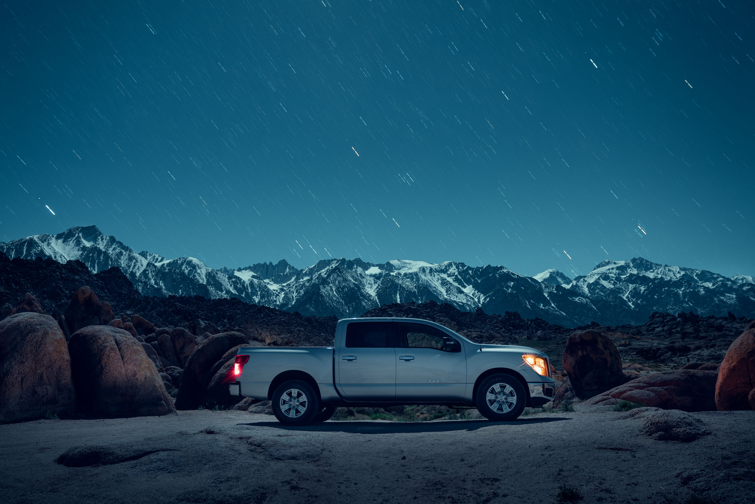 Silver Nissan pickup truck in the Alabama Hills desert at night in front of Mt Whitney full of stars.